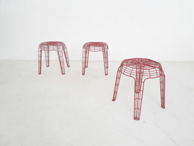 Set of three red metal wire stools